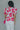 Back view of model wearing the Nothing Compares Floral Top which features white brocade fabric with a fuchsia and red floral print, white lining, round neckline with a v-cutout and short puff sleeves.