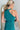 Back view of the Tell Me About It Dress that features a teal ribbed material, a high round neckline, a sleeveless design with one shoulder thick strap, a tight fit, and a mini length.