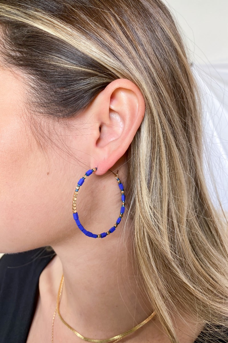 Side view of the Winter Skies Earrings features gold hoop filled with blue and gold beads. 