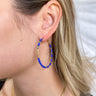 Close up view of the Winter Skies Earrings features gold hoop filled with blue and gold beads. 