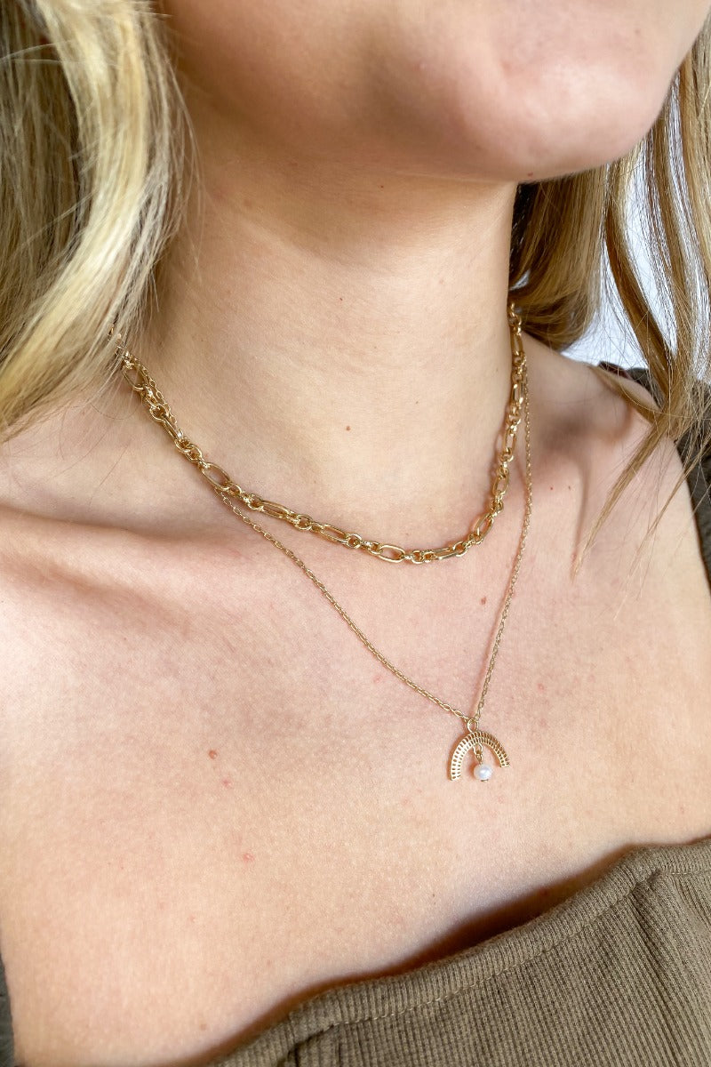 Close up view of the Sunny Side Up Necklace which features double layer, gold chain links and a half crescent medallion with a pearl.