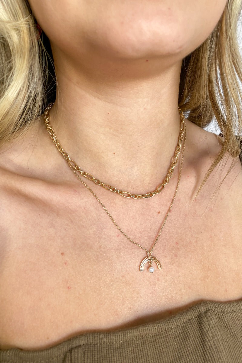 Close up view of the Sunny Side Up Necklace which features double layer, gold chain links and a half crescent medallion with a pearl.