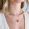 Close up view of model wearing the You're My Rock Necklace which features double gold chain layer with a grey rock.