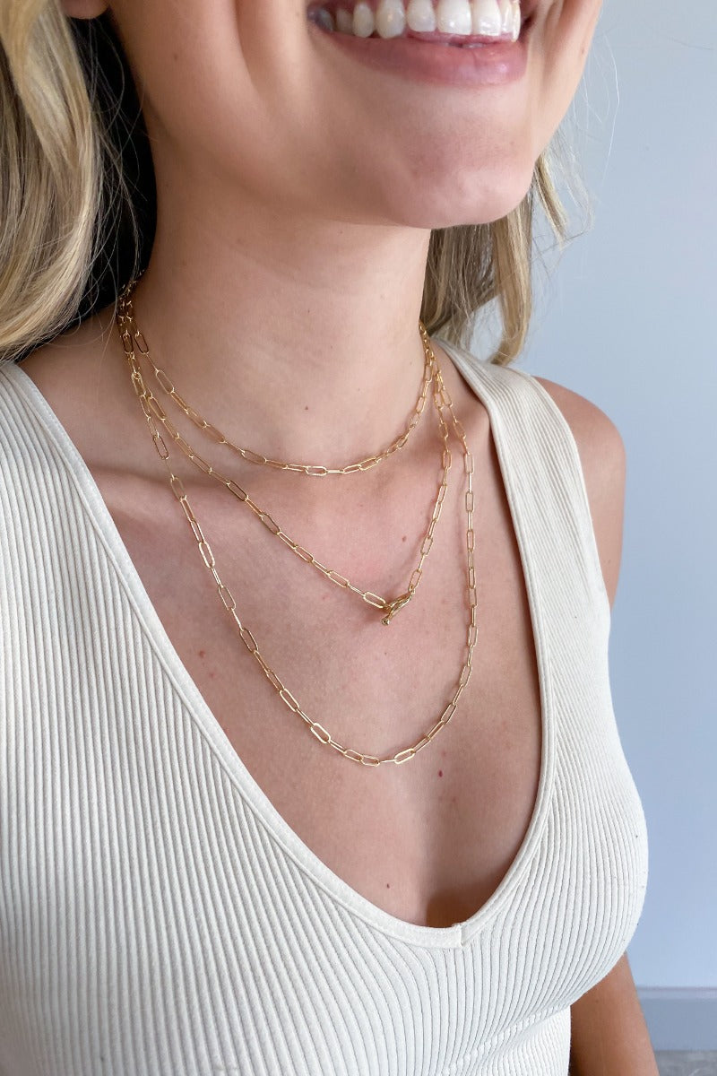 Side view of model wearing the One Last Time Necklace which features triple layer with gold chain links and an open circle. 