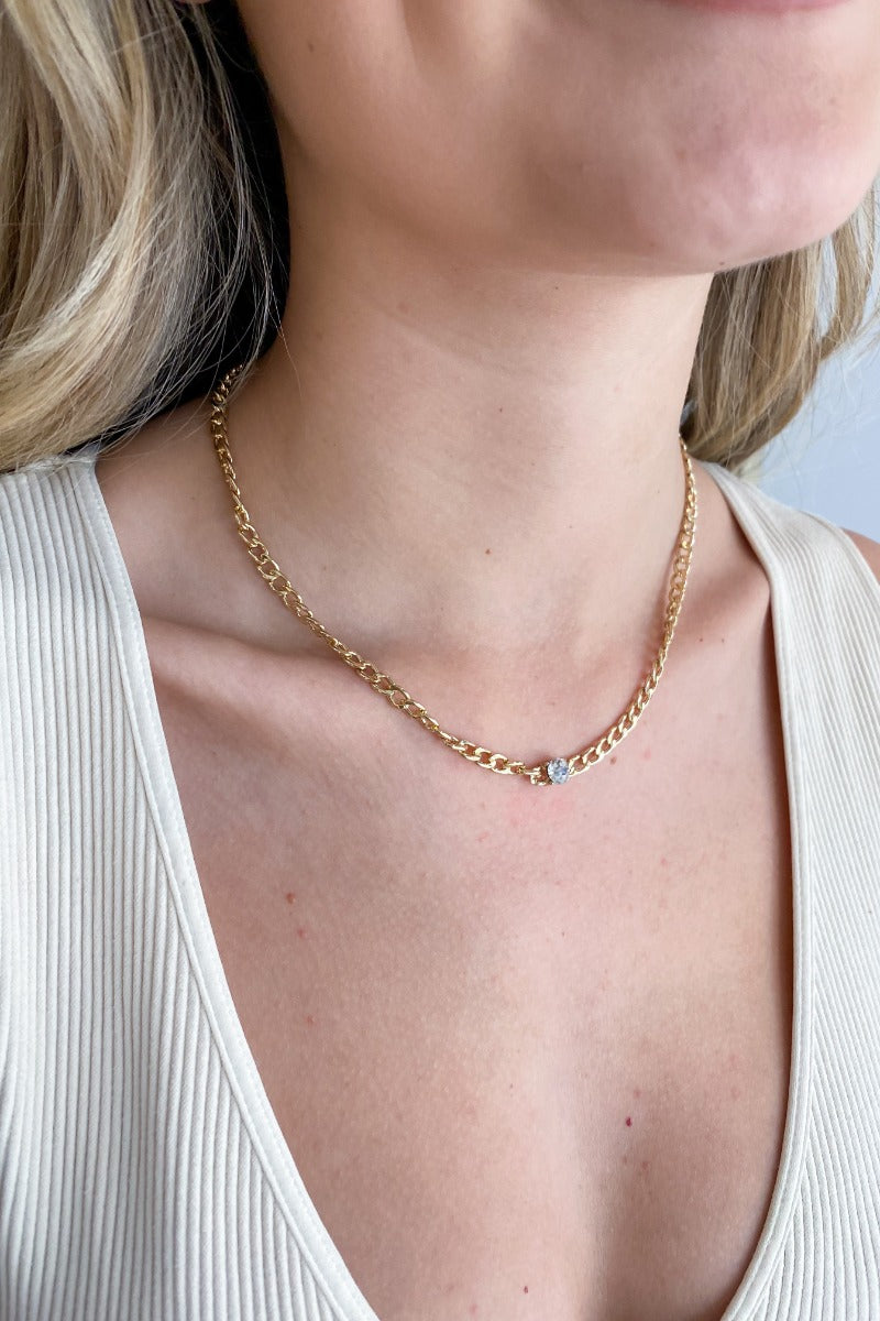 Close up view of model wearing the Break The Chain Necklace which features gold mini chain links with a clear stone.