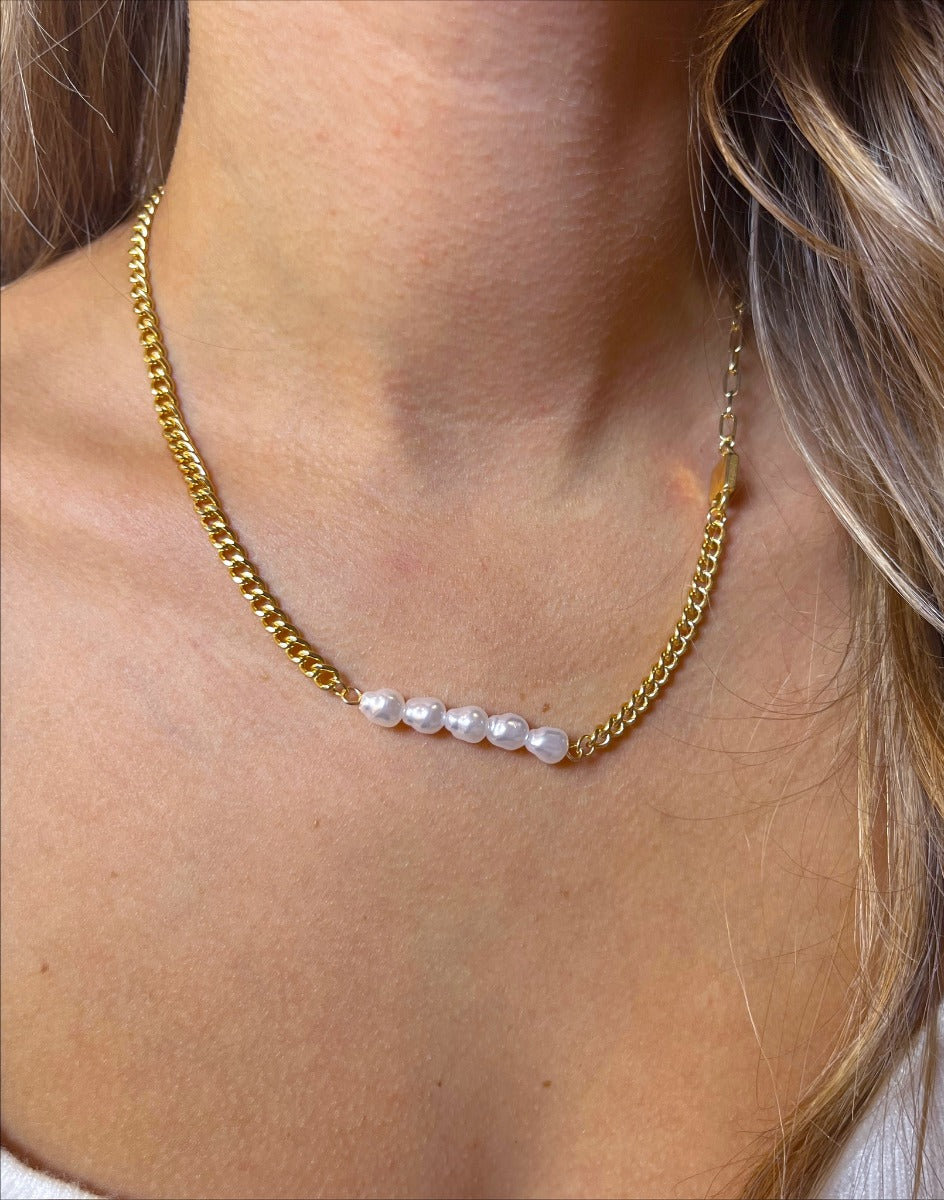 Close up view of model wearing the Keep A Secret Pearl Necklace which features two different gold chain designs linked with pearls and a gold lock.