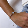 Front view of model wearing the Cold As Ice Bracelet which features iridescent and gold beads with an adjustable string.