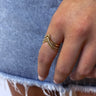 Close up view of model wearing the Wishful Thinking Ring which features three-layered gold ring bands chevron shaped with clear stones and bead details.