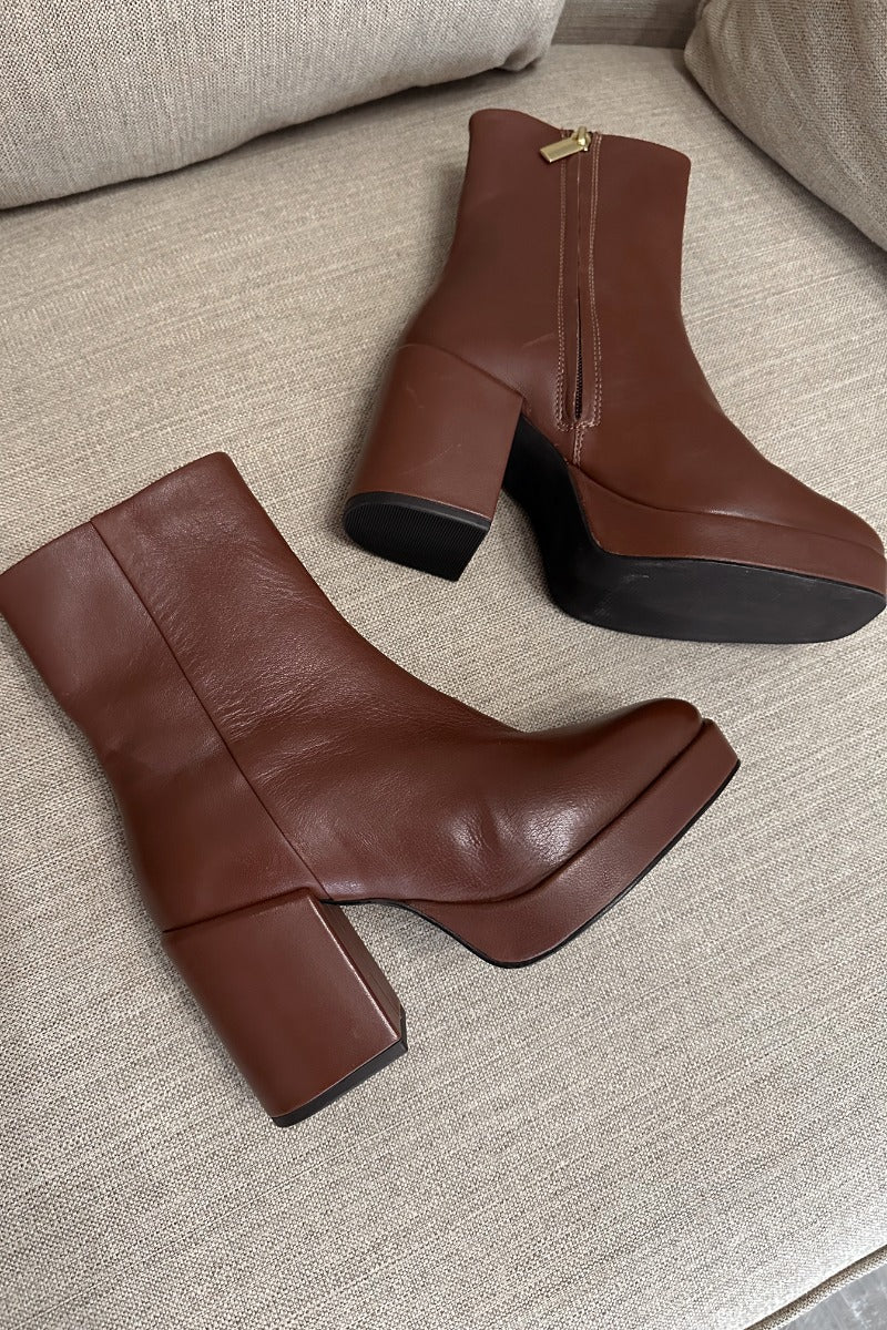 Close up view of the Sweet Lady Leather Boot in Brown which features brown leather upper fabric, monochrome rubber sole, block heel, square toe and inside side zipper closure. 