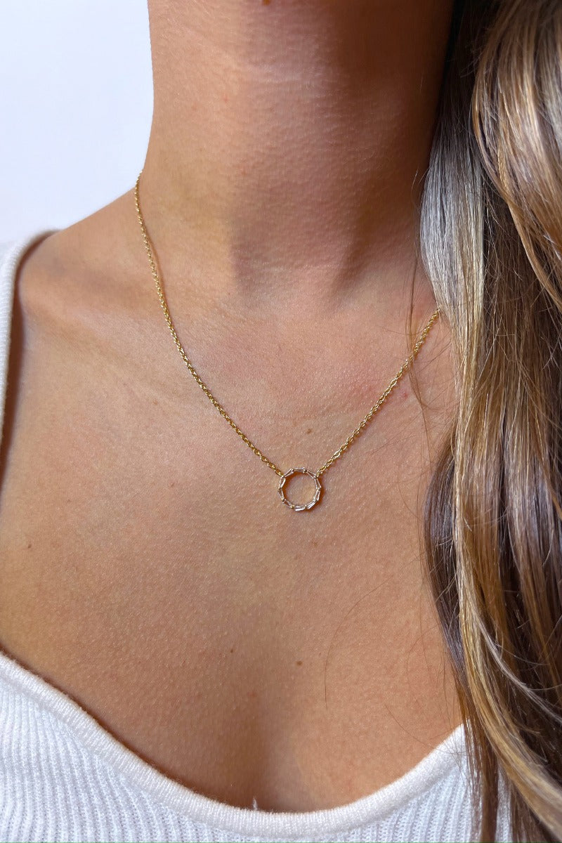 Front view of model wearing the Full Circle Necklace which features one layered gold chain link with open circle medallion with clear stones.