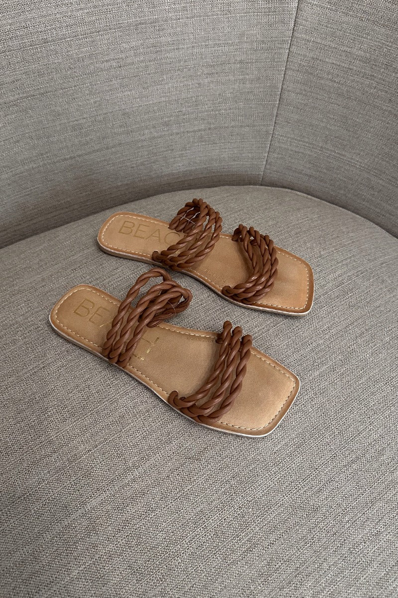 Front lay view of the Amalia Flat Sandal in Tan which features light brown braided upper, two straps, slide-on style and flat sole. 