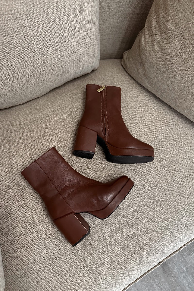 Front lay view of the Sweet Lady Leather Boot in Brown which features brown leather upper fabric, monochrome rubber sole, block heel, square toe and inside side zipper closure. 