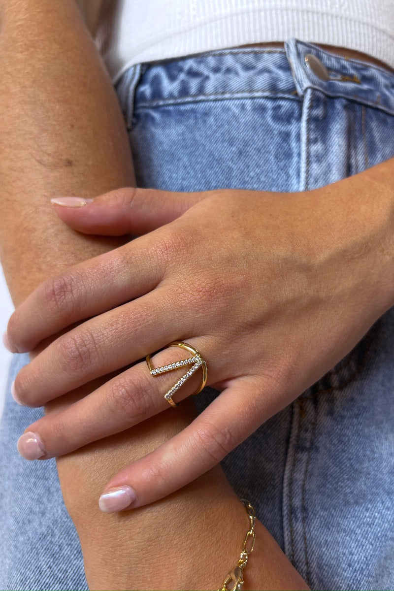 Close up view of model wearing the Sweet Dreams Ring which features two-layered gold ring bands connected with a v design with clear stones.