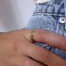 Close up view of model wearing the Change My Mind Ring which  features three-layered gold ring bands with clear stones and clear stone medallion.