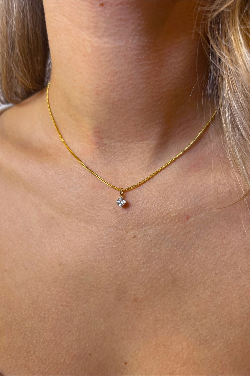 Front view of model wearing the Let It Shine Necklace which features double-layered with gold chain link and gold flat layer with a clear rhinestone attachment.