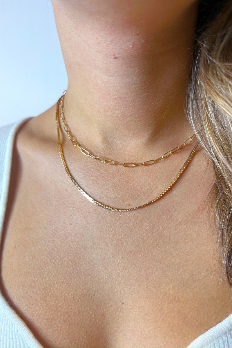 Front view of model wearing the Set For Life Necklace which features double-layered gold chain link with chain links and flat gold braided design.