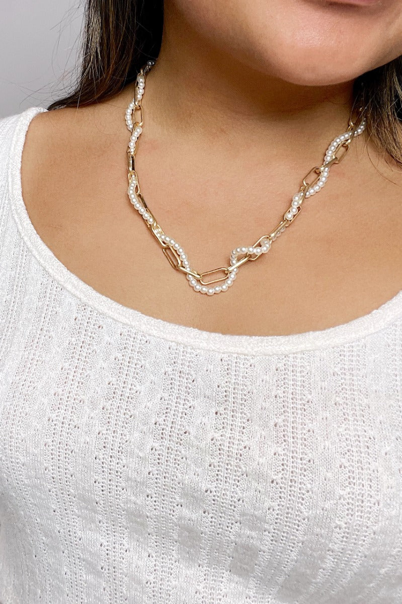 Front view of model wearing the Feel The Love Pearl Necklace which features one layer with pearls and one layer of gold chains intertwined together making one layer.