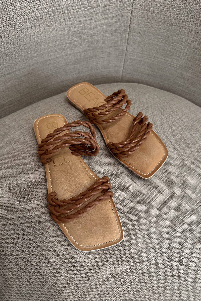 Front lay view of the Amalia Flat Sandal in Tan which features light brown braided upper, two straps, slide-on style and flat sole. 