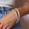 Front view of model wearing the Meant to Be Bracelet Set in Silver which features two layered, silver shimmer metal, skinny bracelets.