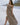 Image shows brunette female model on beach. Model is wearing a brown maxi dress.