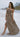 Image shows brunette female model on beach. Model is wearing a brown maxi dress.