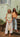 two models standing by stairs wearing green & orange tank top.