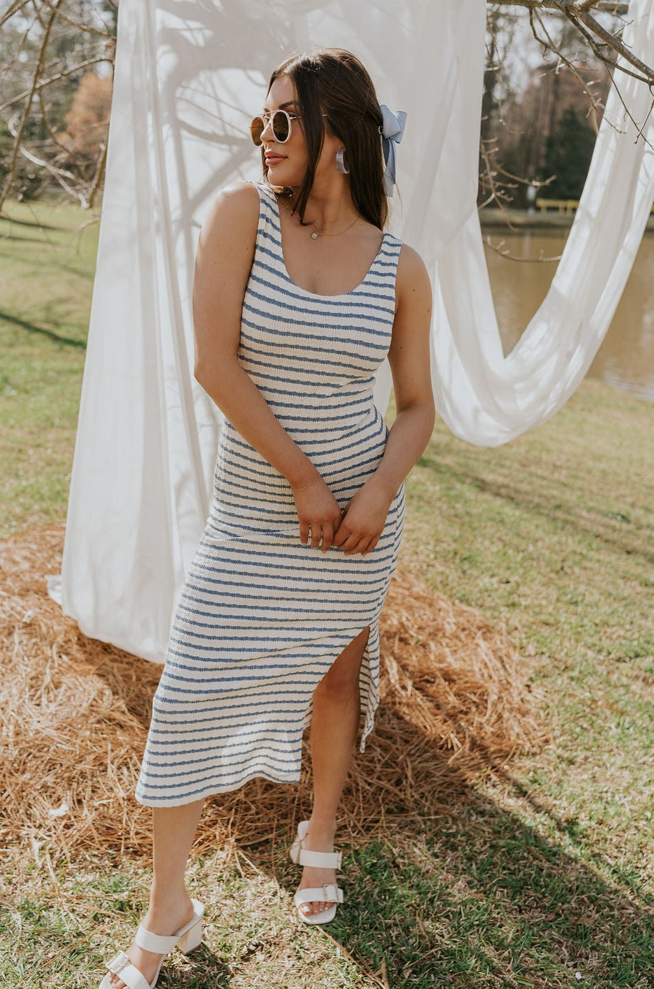 Brunette female model is wearing a white and blue striped midi dress.