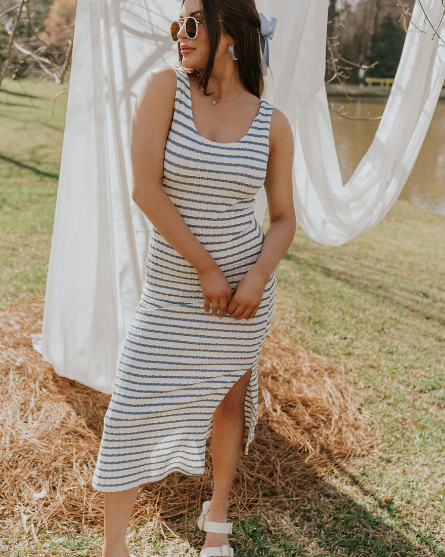 Brunette female model is wearing a white and blue striped midi dress.