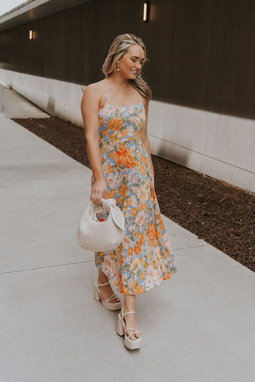 Full body front view of female model wearing a floral midi dress and cream block heels