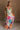 Blonde female model is wearing a pleated multi-color floral maxi dress