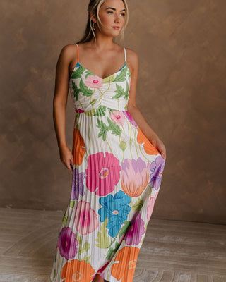 Blonde female model is wearing a pleated multi-color floral maxi dress