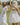 Image shows 2 young women outside in field. left woman is wearing a white maxi dress and left woman has her back turned and is wearing a white mini dress.