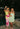 models standing arm in arm in green dresses