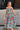 Full body front view of female model wearing a colorful printed maxi dress.