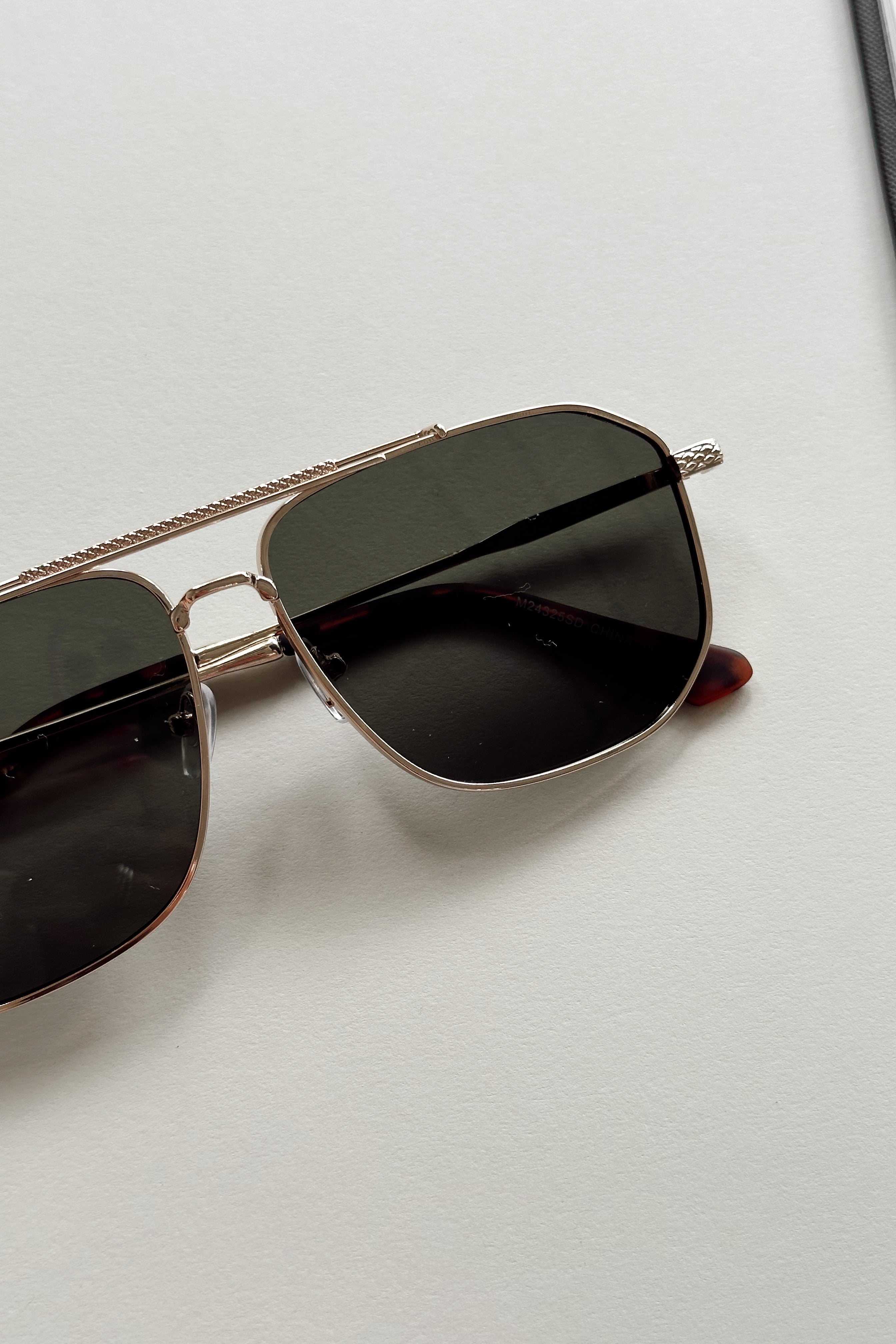 Regan Sunglasses in Gold & Black - flat lay - close up front view