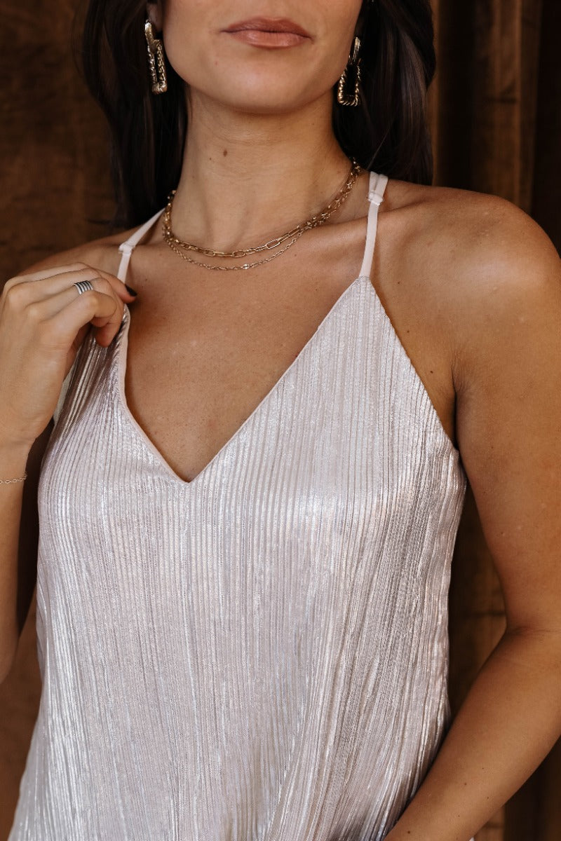 Close upper front view of model wearing the Kenzie Champagne Shimmer Tank Top that has champagne shimmer ribbed fabric, nude lining, a v-neckline, and adjustable straps.
