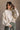Front view of model wearing the Kaitlyn Beige Turtleneck Sweater that has beige knit fabric, ribbed hem, a ribbed turtleneck neckline, and long sleeves with ribbed cuffs.