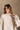 Upper front view of model wearing the Kaitlyn Beige Turtleneck Sweater that has beige knit fabric, ribbed hem, a ribbed turtleneck neckline, and long sleeves with ribbed cuffs.
