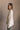 Side view of model wearing the Kaitlyn Beige Turtleneck Sweater that has beige knit fabric, ribbed hem, a ribbed turtleneck neckline, and long sleeves with ribbed cuffs.