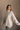Side view of model wearing the Kaitlyn Beige Turtleneck Sweater that has beige knit fabric, ribbed hem, a ribbed turtleneck neckline, and long sleeves with ribbed cuffs.