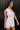 Side view of model wearing the Harper Off White Sleeveless Mini Dress which features white denim fabric, mini length, scooped slit, round neckline with scoop detail, sleeveless and monochrome back zipper with hook closure.