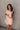 front view of model wearing the Rory Blush Ruffle Sleeveless Mini Dress that has blush cotton fabric, mini length, square neckline, ruffle straps, sleeveless and smocked back.