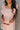 Close front view of model wearing the Rory Blush Ruffle Sleeveless Mini Dress that has blush cotton fabric, mini length, square neckline, ruffle straps, sleeveless and smocked back.