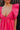 Close up view of model wearing the Stella Hot Pink Ruffle Straps Mini Dress which features hot pink light weight fabric, mini length, hot pink lining, two side pockets, sweetheart neckline, ruffle straps, sleeveless and open back with tie closure.