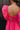Close up back view of model wearing the Stella Hot Pink Ruffle Straps Mini Dress which features hot pink light weight fabric, mini length, hot pink lining, two side pockets, sweetheart neckline, ruffle straps, sleeveless and open back with tie closure.