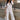 Full body view of model wearing the Bella Ivory Plunge Neckline Flare Jumpsuit which features white knit fabric, plunge neckline, short flare sleeves, open back, monochrome back zipper with hook closure and flare pant legs.