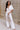 Full body view of model wearing the Bella Ivory Plunge Neckline Flare Jumpsuit which features white knit fabric, plunge neckline, short flare sleeves, open back, monochrome back zipper with hook closure and flare pant legs.