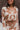 Close-up front view of model wearing the In Your Dreams Top, that has an ivory knit material, a mocha geometric print, a collar neck, a long sleeve, and a button-up front. Worn over whit tank with with matching skirt.