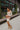 Full body side view of model wearing the Take Your Time Dress, which features an ivory knit material, a taupe striped pattern, a straight neckline, a long sleeve, a mini length, and a tight fit.