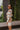 Side view of model wearing the Take Your Time Dress, which features an ivory knit material, a taupe striped pattern, a straight neckline, a long sleeve, a mini length, and a tight fit.